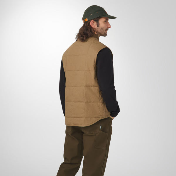Man wearing a brown puffer vest, black shirt, and green cap on a white background