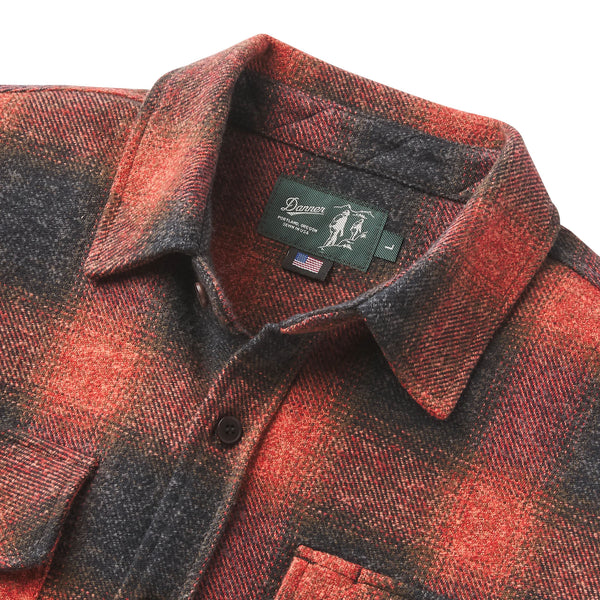 Close-up of a collared button-front shirt jacket in a red and dark gray/black plaid pattern, with a visible neck label reading Denim.