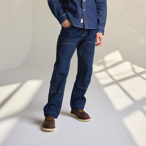 Danner - Danner Kenton Double Knee Pant Dark Indigo - Person wearing blue jeans and a denim shirt standing in a room with sunlight casting shadows on the wall. - Alternative View 1