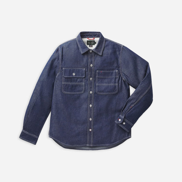 A dark indigo blue denim long-sleeve button-up shirt with two chest pockets, laid flat on a light gray background.