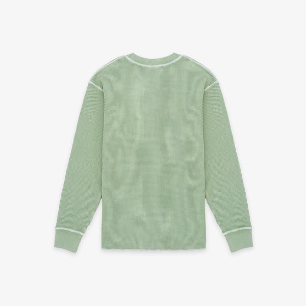 A sage green ribbed knit long-sleeve shirt with white contrast stitching on the shoulders, cuffs, and collar, shown flat against a light gray background.