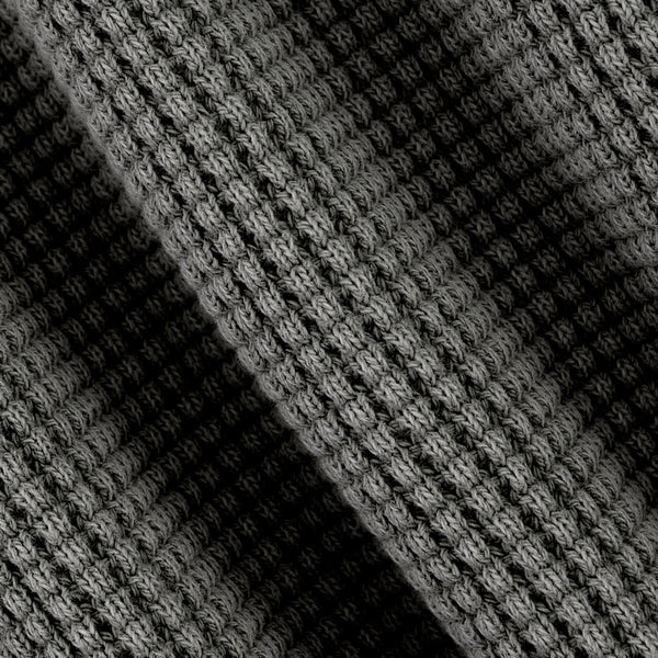 Close-up of a black and gray textured knit fabric with a diagonal shadow creating contrast.