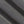 Load image into Gallery viewer, A close-up of dark gray textured fabric with soft diagonal folds showing the woven material detail.
