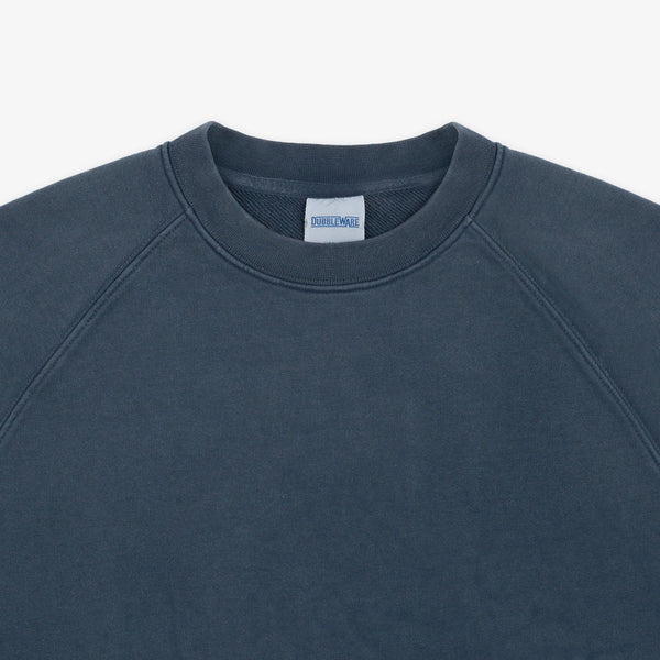 Close-up of a crewneck sweatshirt in a dark slate blue-gray color, showing the inner neck label which reads 'SWEATSHIRTS'.