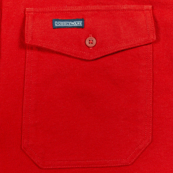 A close-up of a bright red fabric pocket with a flap closure and a small button, featuring a visible DUBBLEWARE label.