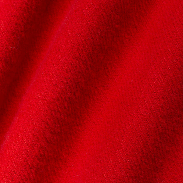 A close-up of bright red textured fabric with soft diagonal folds and a plush, nubby surface.