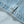 Load image into Gallery viewer, Close-up of light blue denim fabric with orange contrast stitching along a folded seam.
