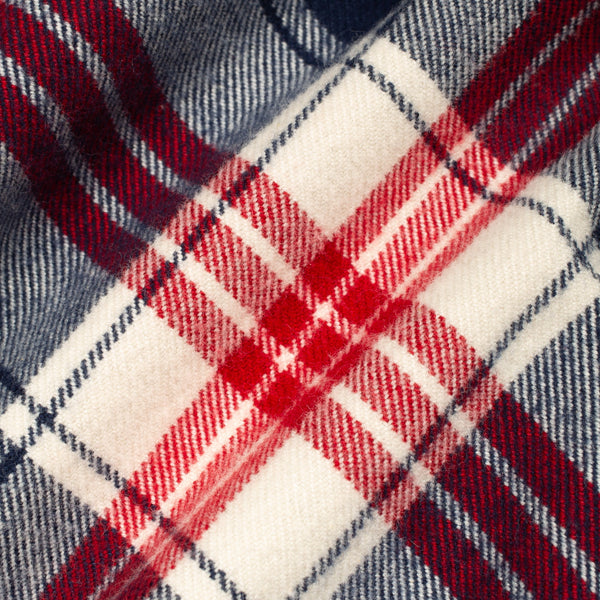 A close-up of a plaid fabric pattern with red, white, and navy blue stripes in a tartan design.
