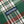 Load image into Gallery viewer, Close-up of a green plaid fabric with red, white, and gray stripes, featuring a navy blue woven label with the brand name 'DUBLEWARE' in white.
