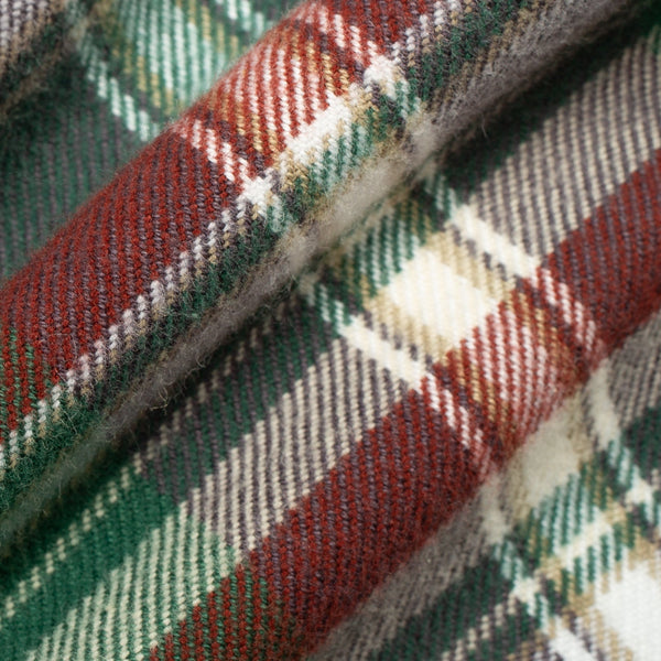 A close-up of a folded plaid fabric with a classic tartan pattern in green, red, beige, and white.