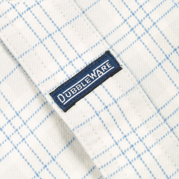 Close-up of a white fabric with a light blue grid pattern and a navy blue brand label reading DUBBLEWARE.