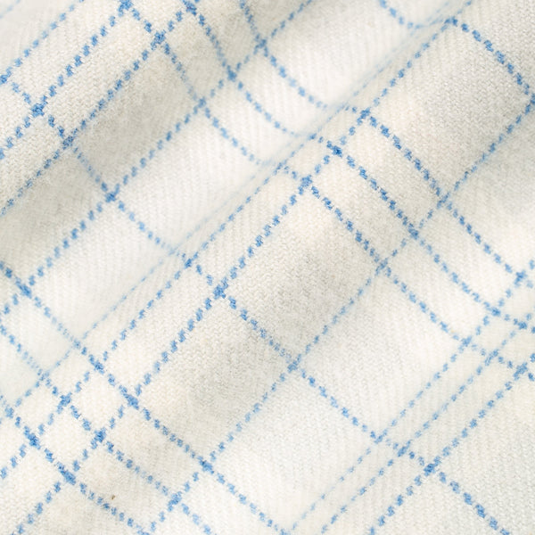 A close-up of a white or off-white woven fabric with a light blue plaid pattern.