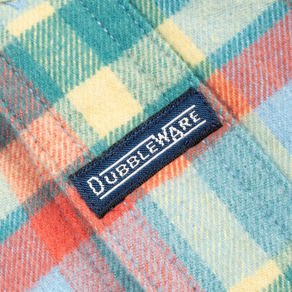 Close-up of a plaid fabric with a black woven label reading DUBLEWARE in white text.