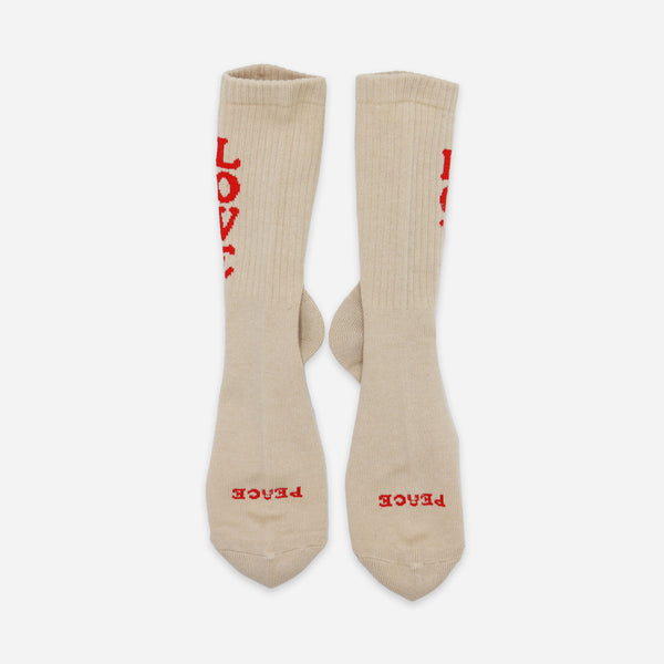 A pair of beige crew socks with red embroidered text, shown flat against a light gray background.