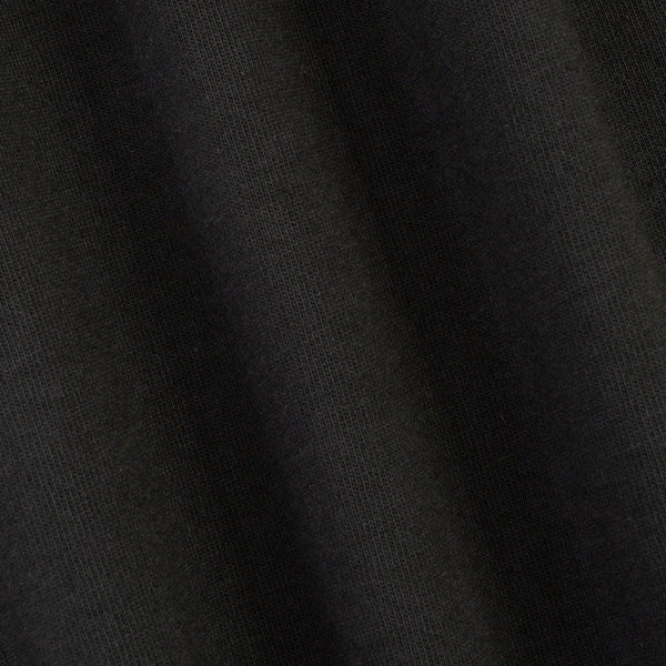 A close-up of dark charcoal gray knit fabric with soft folds showing the fine ribbed texture.