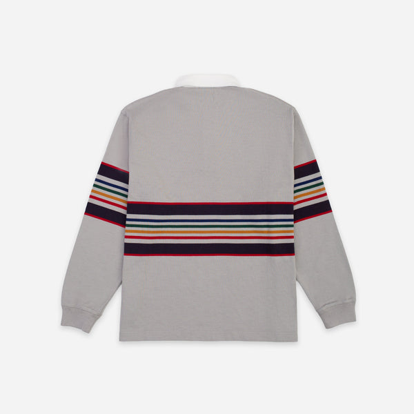 A light gray long-sleeve rugby shirt shown from the back, featuring a horizontal multicolor stripe pattern across the back and upper sleeves.