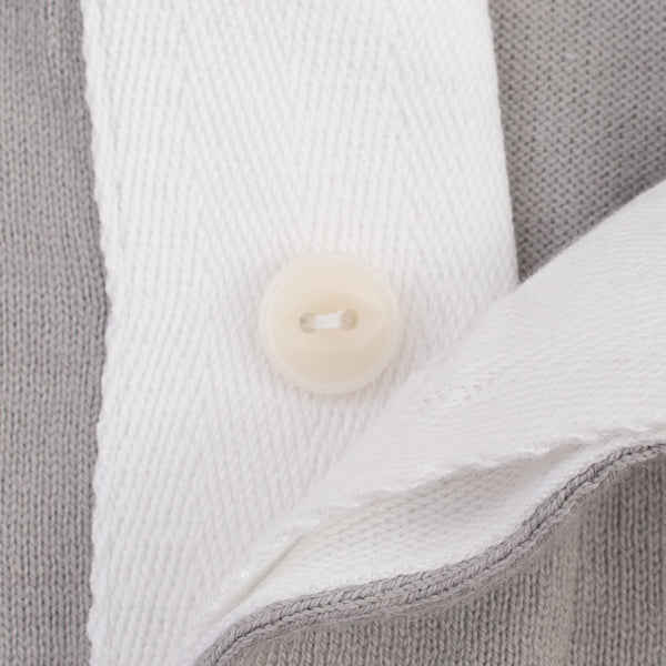 Close-up of a gray knit garment with a white collar and a round off-white button.