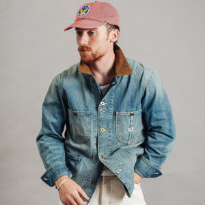 Double RL By Ralph Lauren - Corduroy Collar Denim Jacket - Wrightsville Wash - A man wearing a blue denim work jacket with a brown corduroy collar, paired with off-white trousers and a dusty pink baseball cap, photographed against a neutral gray studio background. - Alternative View 1