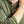 Load image into Gallery viewer, Close-up of a person wearing an olive green waffle-knit long-sleeve henley shirt, with the collar open, buttons visible, and one arm raised wearing a silver chain bracelet.
