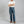 Load image into Gallery viewer, A man wearing a white t-shirt, blue jeans, brown shoes, and a black baseball cap stands with arms crossed against a plain gray studio background.
