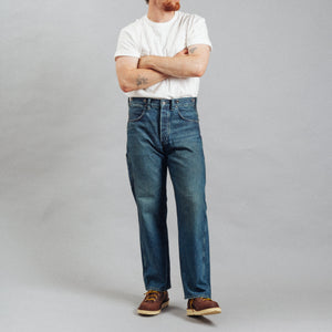 Double RL By Ralph Lauren - RRL Richmond Straight Fit Jean Learoy Walsh - A man wearing a white t-shirt, blue jeans, brown shoes, and a black baseball cap stands with arms crossed against a plain gray studio background. - Alternative View 1