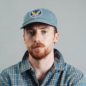 Double RL By Ralph Lauren - RRL Garment-Dyed Twill Ball Cap Midnight Blue - A man with a red beard and blue eyes wearing a light blue baseball cap with a circular 'HPL' logo patch and a blue and green plaid shirt, photographed against a solid gray background. - Alternative View 1